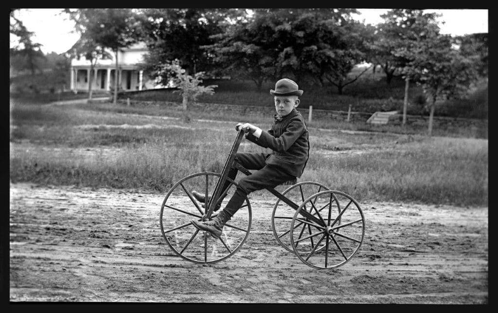 Boy from the from the mid-19th century riding a tricycle