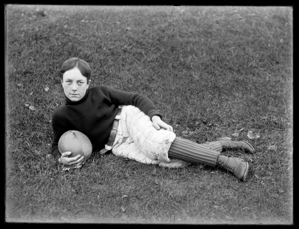 Young man from the 19th century with either Rugby or football clothing and ball.